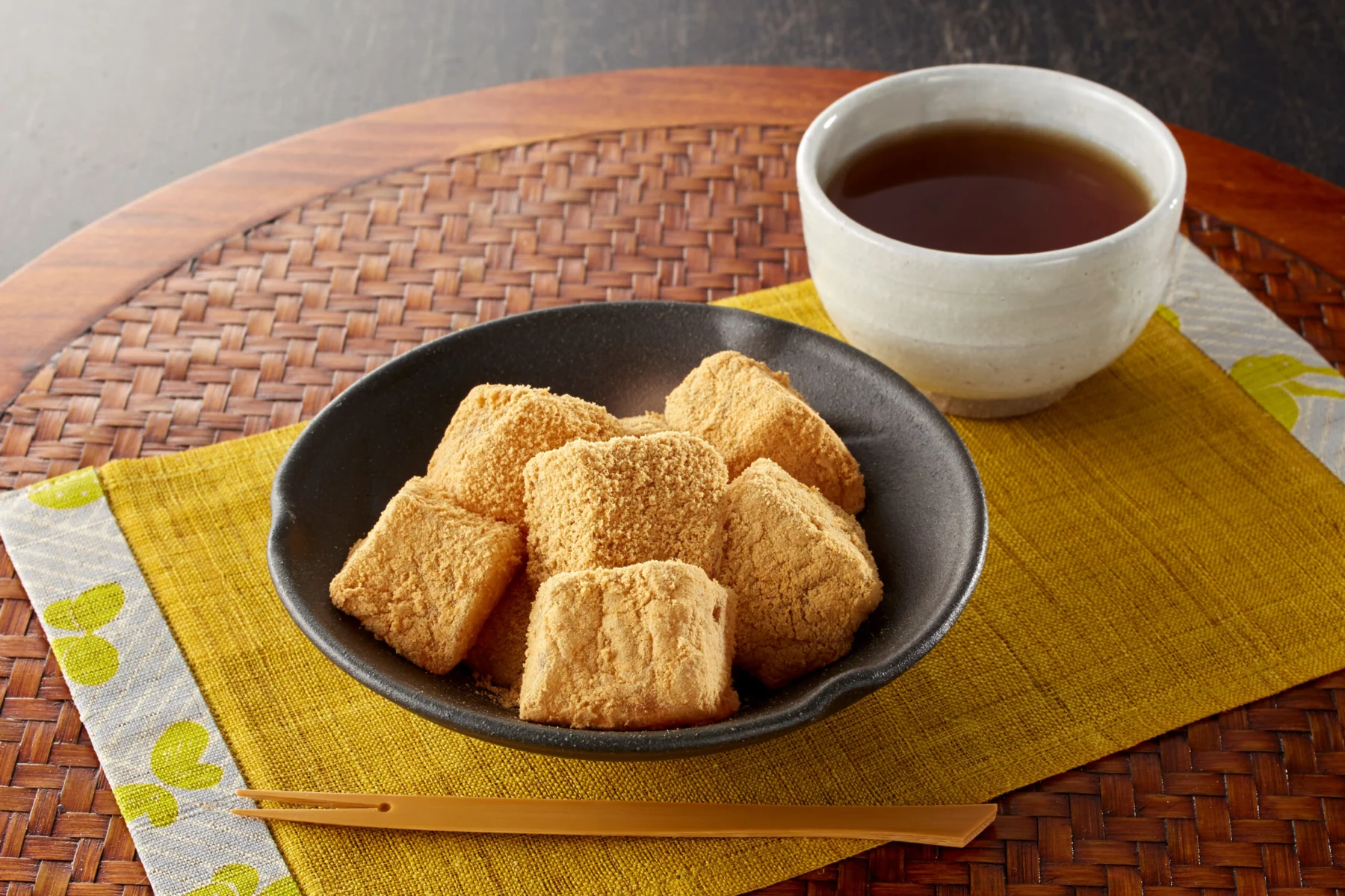 湯呑みに淹れたほうじ茶とお茶請けの菓子が並ぶ穏やかなティータイム